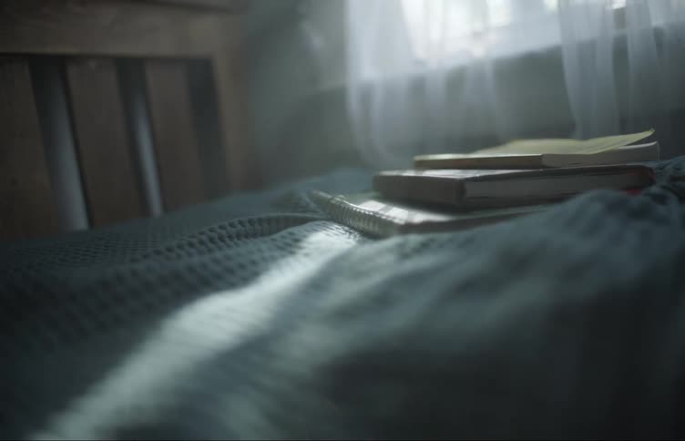 School textbooks sit on a bed near a window