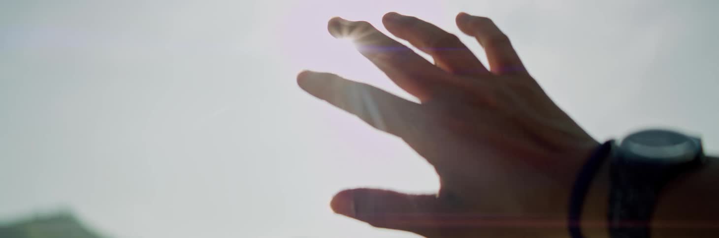 A person putting their hand up at the sun