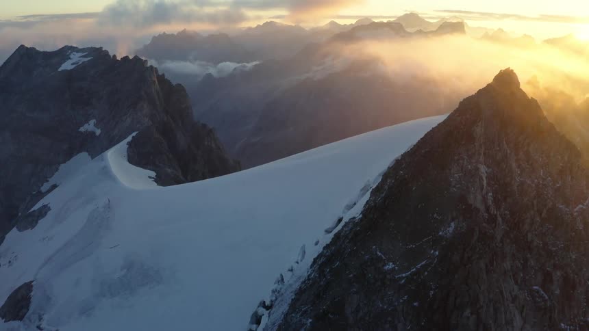 An aerial view of a snow covered mountain range as the sun sets