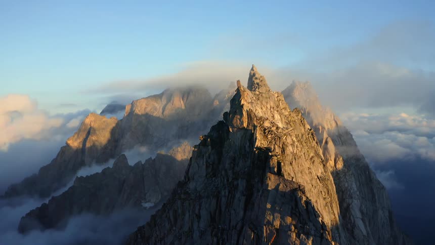 Fog covers valleys as sun brightens one face of mountain ridge