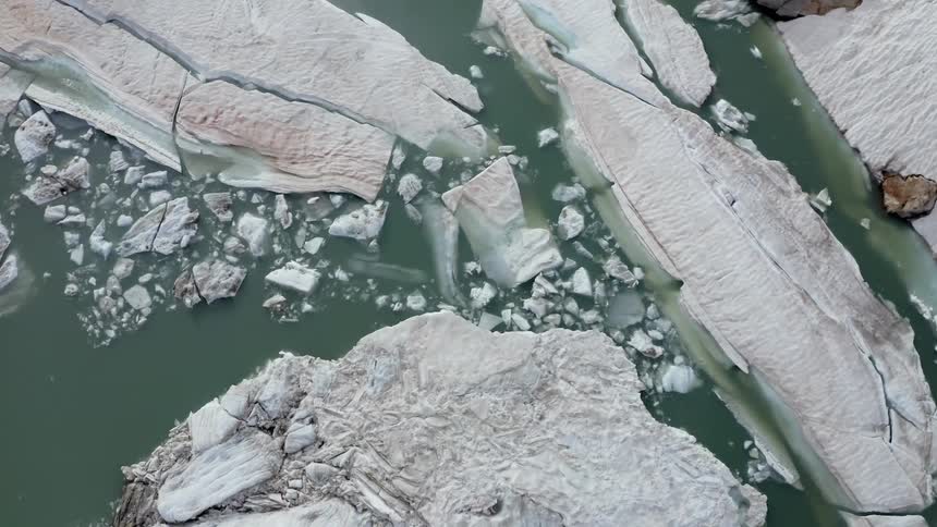 Icebergs float of reflective water near glacier