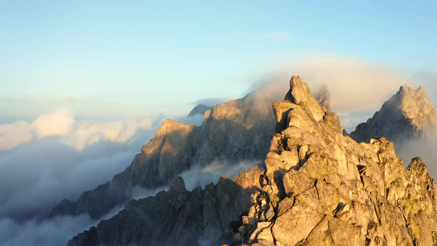 An aerial view of mountain range surrounded by clouds