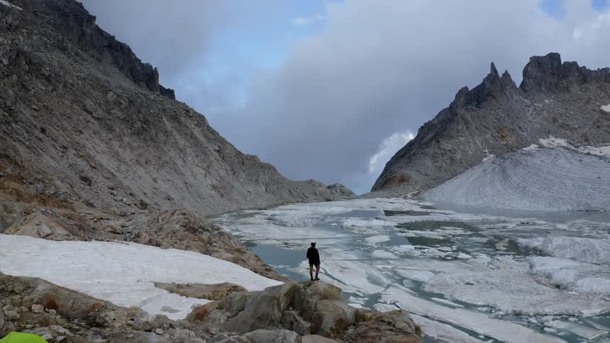 A person stands on the rocks at the peak