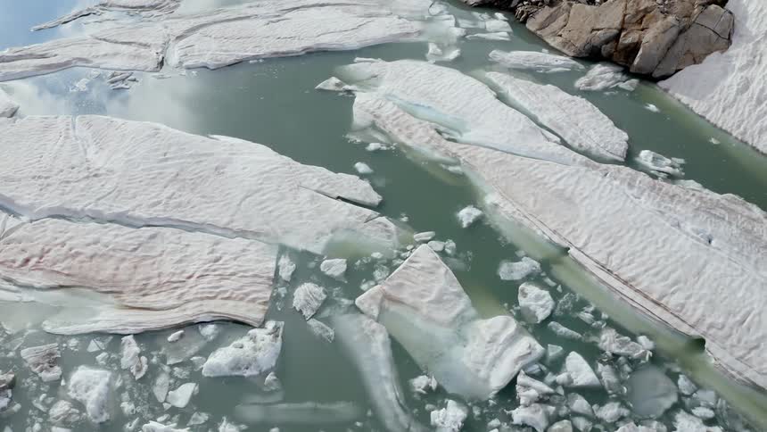 An aerial view of chunks of ice in the water along the shore