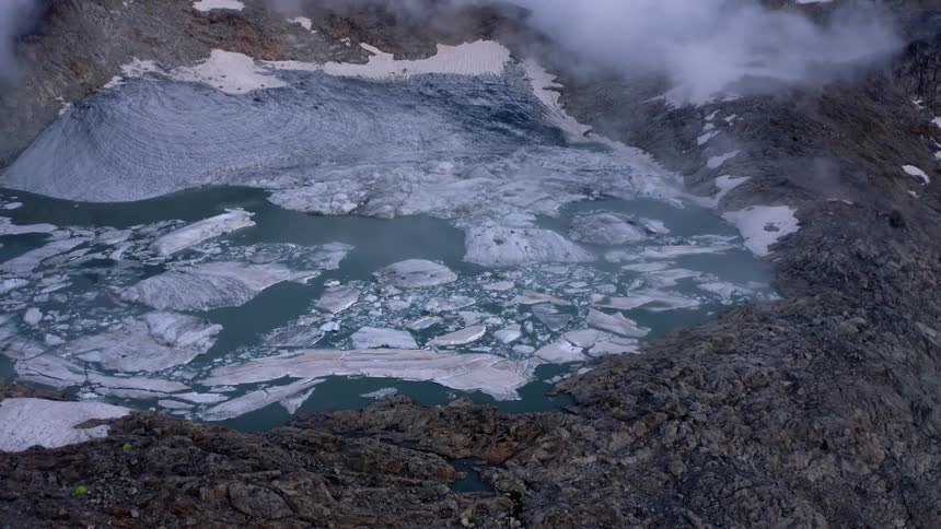 Low lying clouds cover part of mountain bordering glacier lake