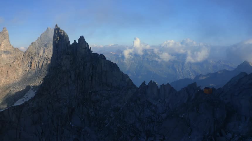 Silhouette of a mountain ridge and mountains in the distance in a cloudy sky