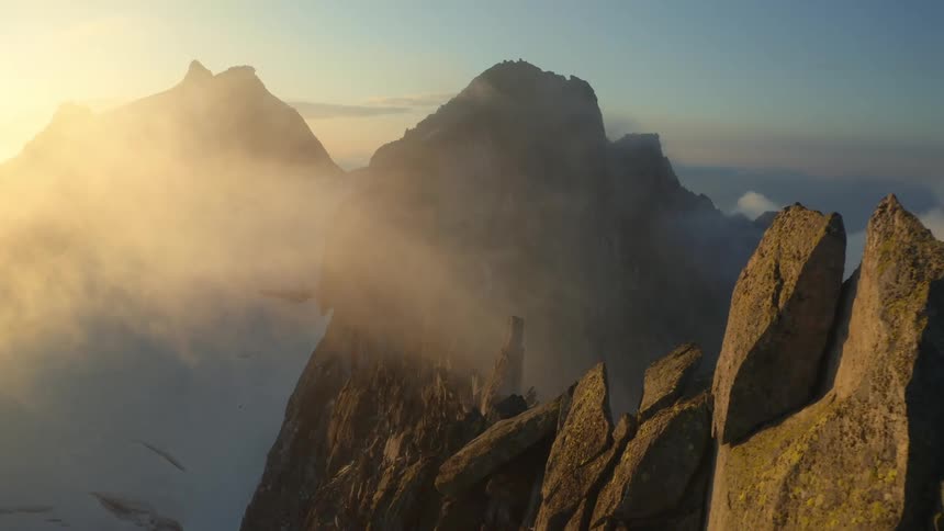 The sun shines on mountains high in the clouds