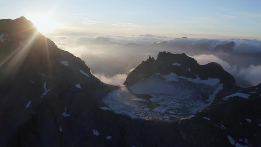 The sun shines on mountains high in the clouds