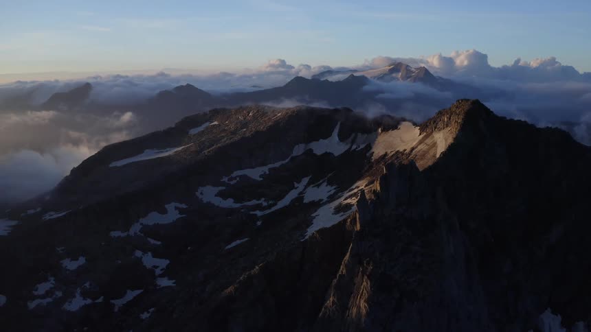 Sunlight shines on the tops of mountain ridges with fog and cloud cover
