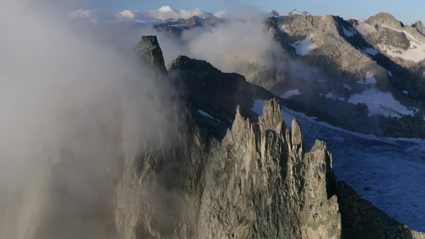 An aerial view of a jagged mountain landscape with snow and ice in the daytime