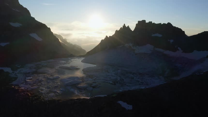 Aerial view of glaciers and mountains being silhouetted against the sun