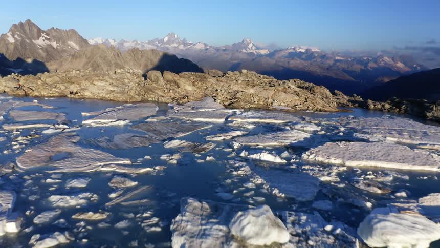 Broken chunks of ice and snow settle in blue sea water