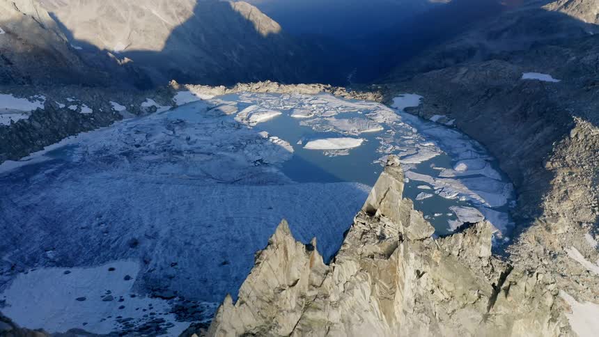 Ice covers lake high in mountains above mist filled valley