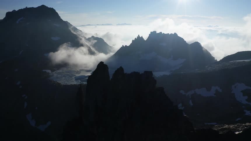 An aerial view of a cloud covered mountain range with a river flowing through