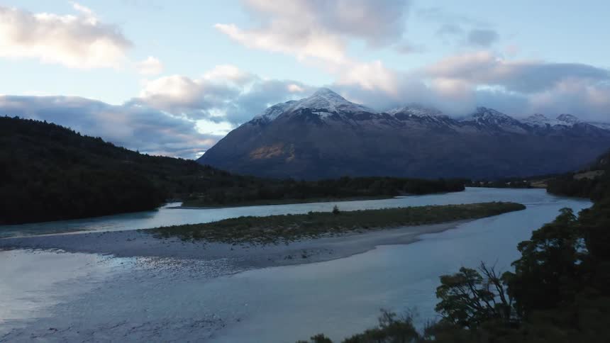 Aerial of the camera proximity flying above pine trees revealing a stunning mountain and river landscape along the Rio Baker in Patagonia Chile