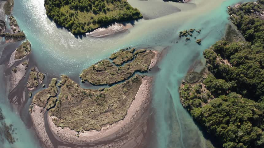 An epic aerial looking straight down on a winding river with mixed sediment and teal clean waters of the Patagonia wilderness