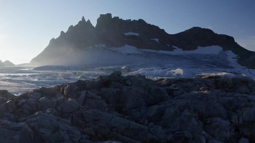 Sun shines across mountain and snow covered water