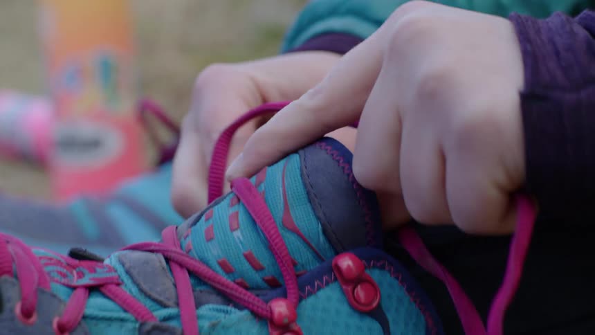 A young hiker laces their boots as they get ready to head into the backcountry on a backpacking trip