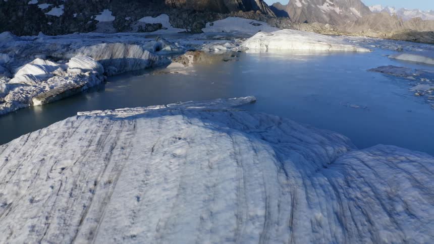 Snow and ice cover water and mountains under clear blue sky