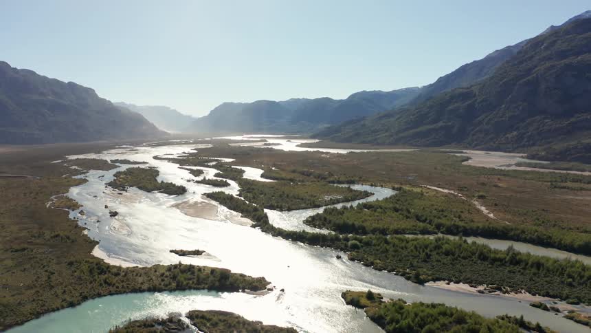 Waterways wind through valley toward misty horizon