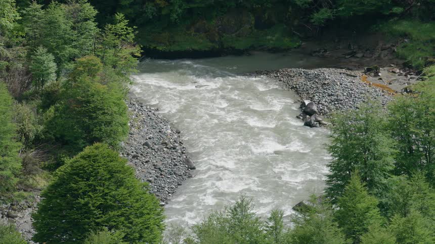 A river quickly rushes down a canyon surrounded by trees