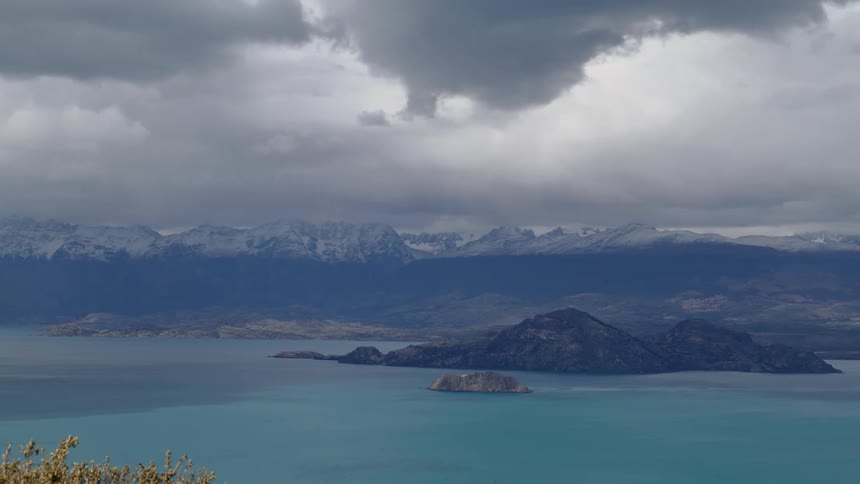 Mist covers ocean island and mountains under cloudy sky