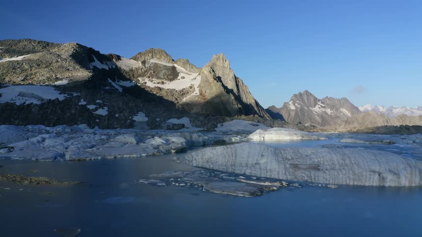 Shadow covers water ice covered shore and base of mountain