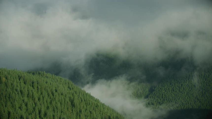 Aerial shot of he hills covered in a thick fog as seen from high above the valley, feels eerie and mysterious