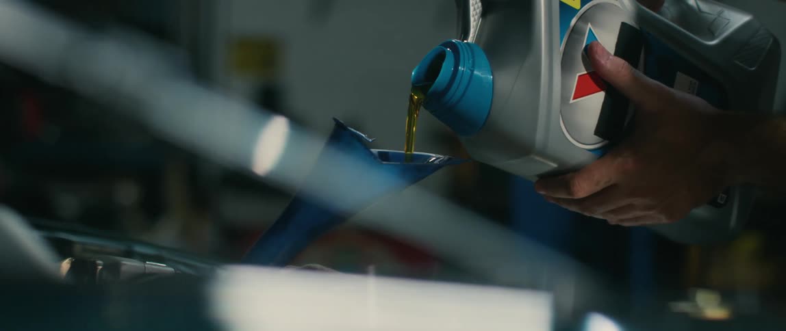 A person pouring oil into an engine