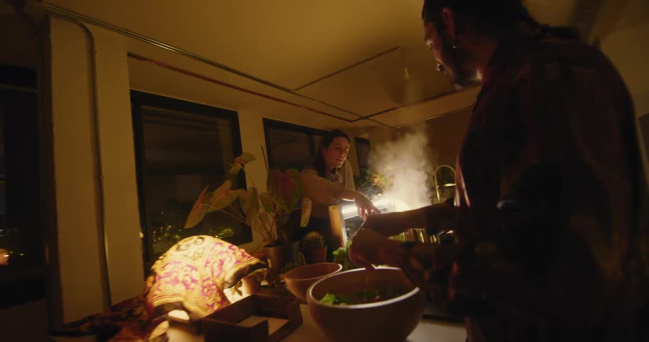 A group of friends gather around a kitchen island and cook together