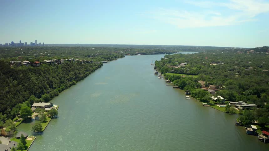 An aerial view of a waterway in the suburbs of a metropolis with a skyline in the background