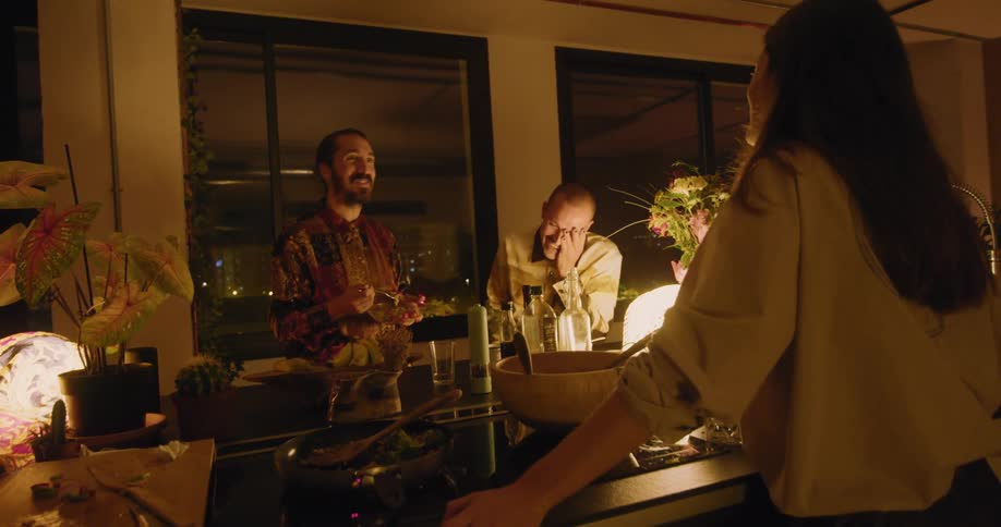 A group of friends in a kitchen talking to each other