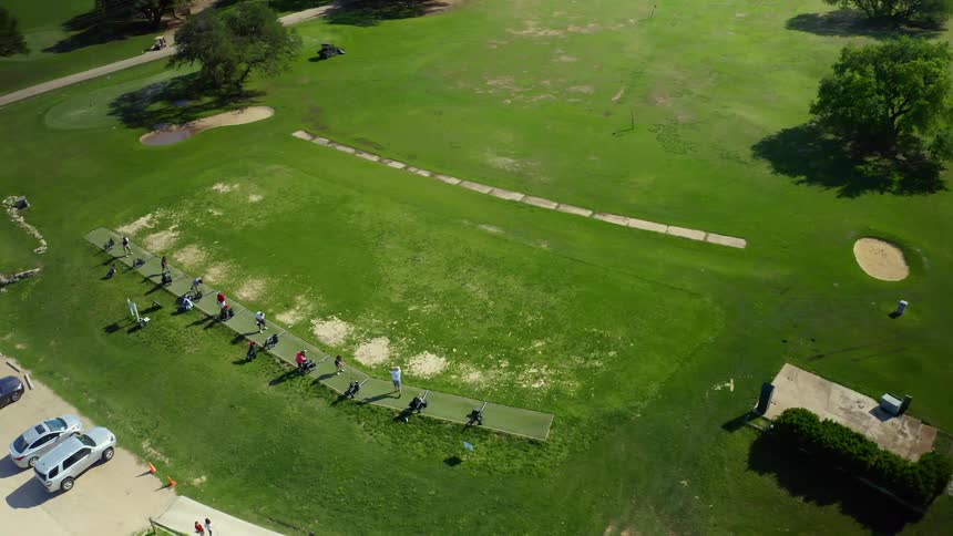 An aerial view of people practicing their golf swing at a sports facility during the daytime