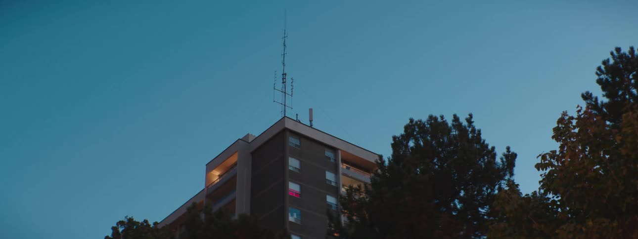 The top floors of a highrise apartment building as seen from the ground at dusk
