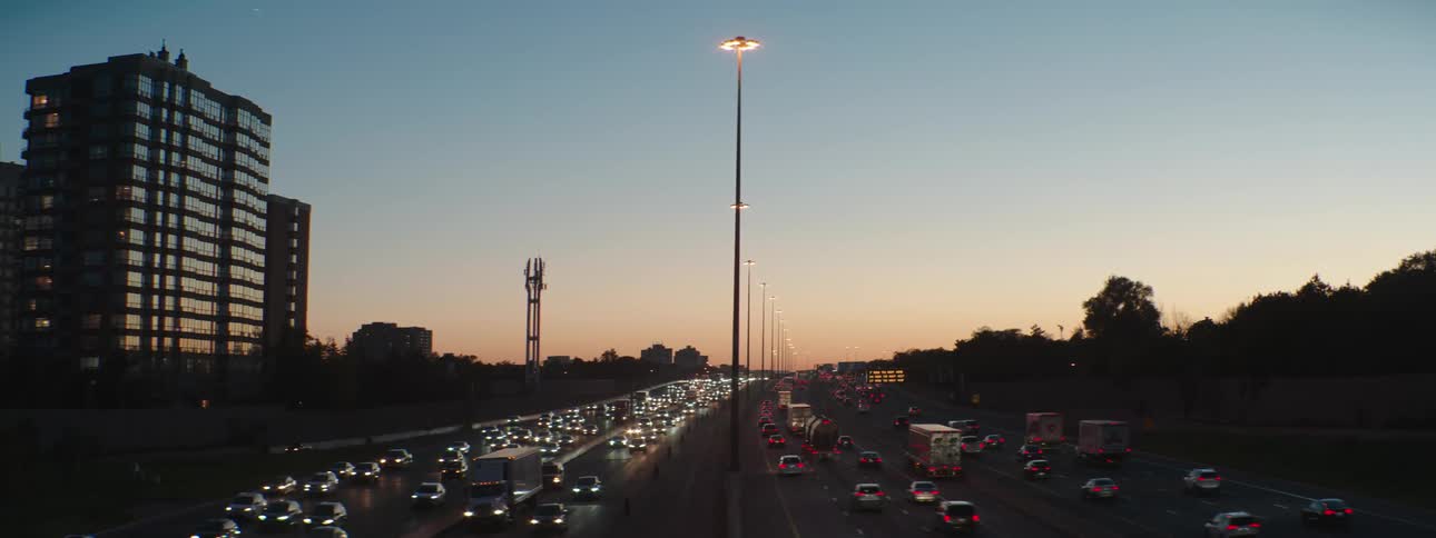 Multilane rush hour highway traffic near a large city at dusk