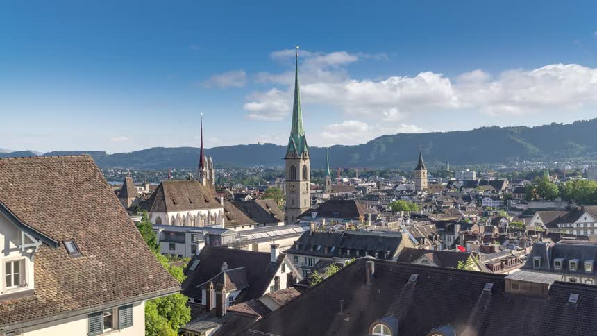 An aerial timelapse view of a neighborhood in a town with a mountain ridge in the background on a sunny day