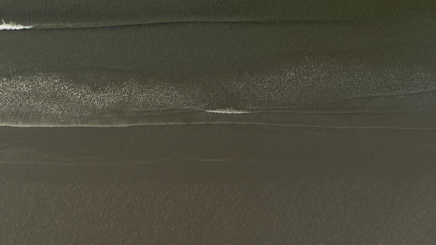 Top down view of gentle ocean waves washing ashore on the beach