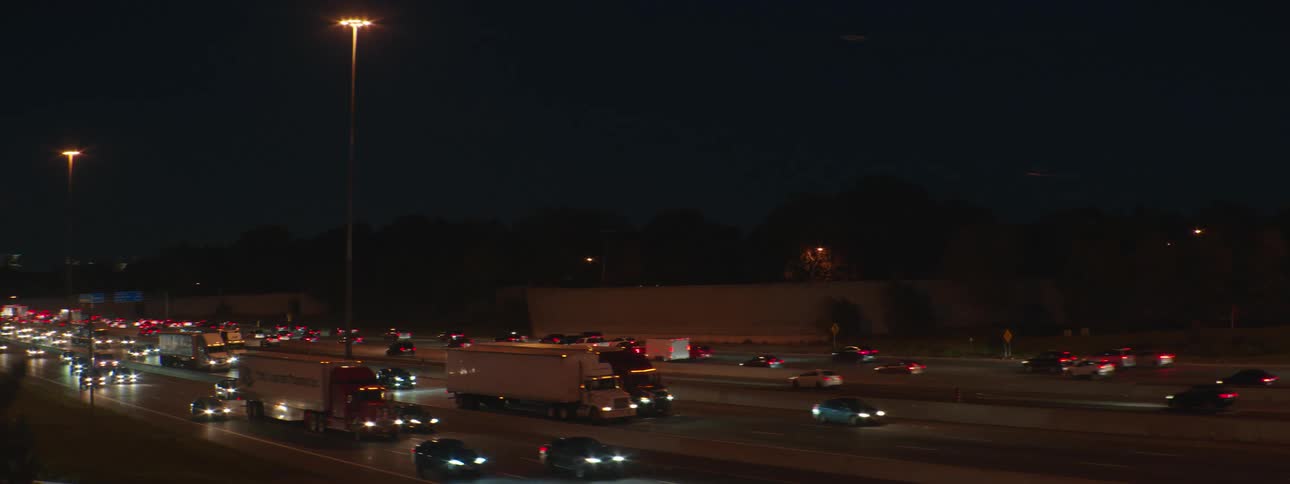 Cars and trucks travel in both direction on a city highway at night