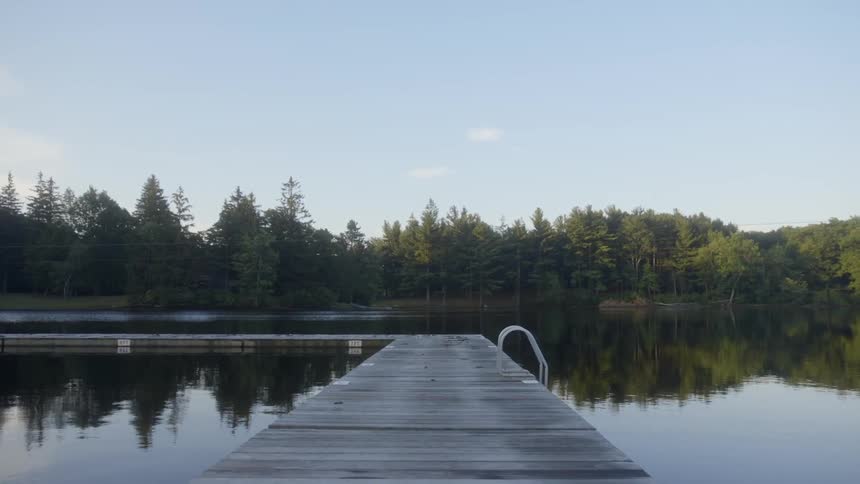 A wooden swimming dock extends out into the lake