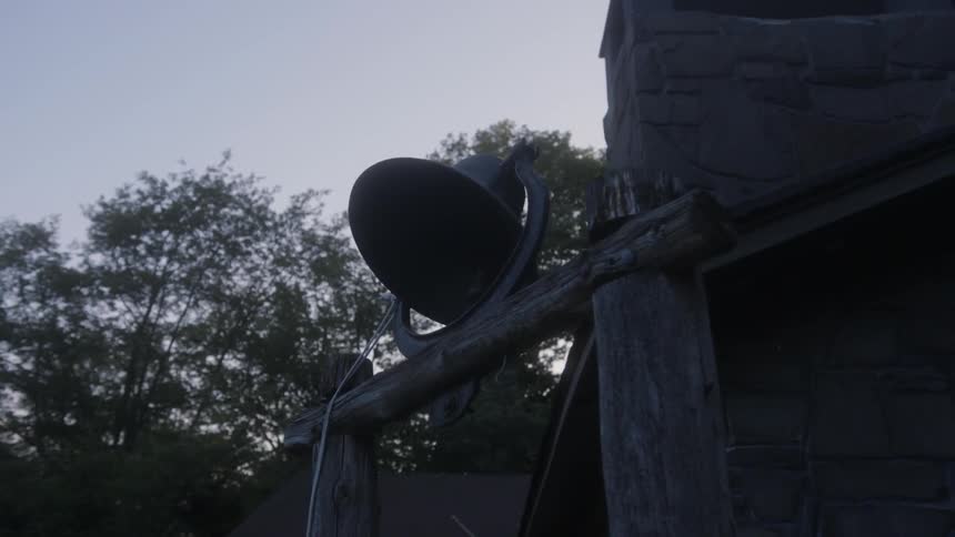 A bell sits next to a stone wall