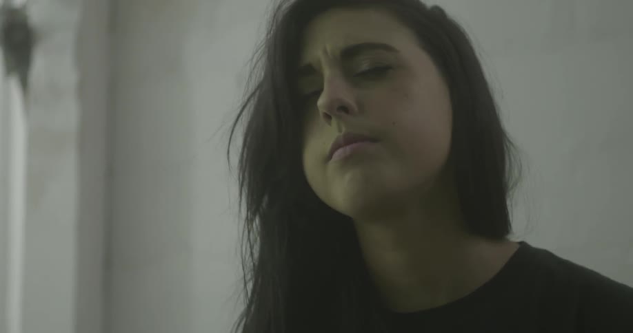 A woman looking down slowly looks up with her eyes closed