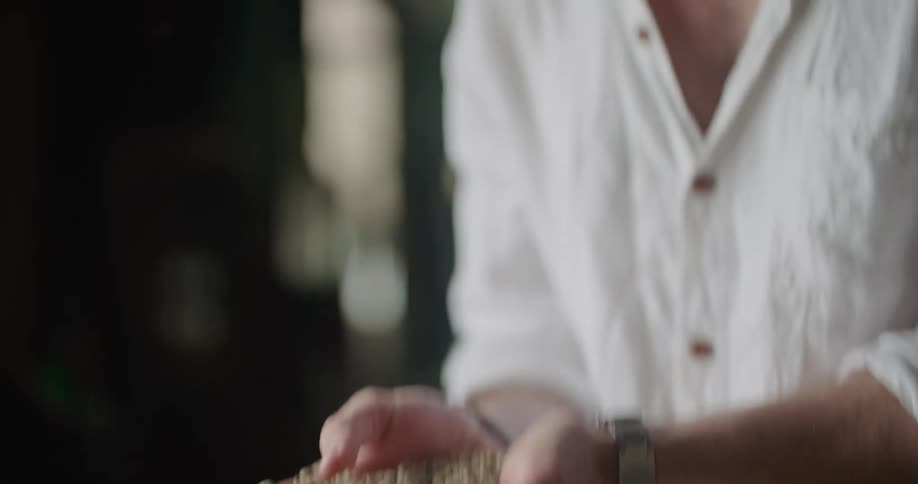 A man examines a handful of coffee beans he holds with palms together