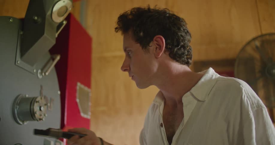 A man removes a small scoop from a machine and smells it