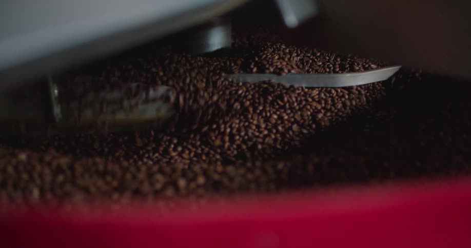 Coffee beans are stirred with paddles in a large contraption