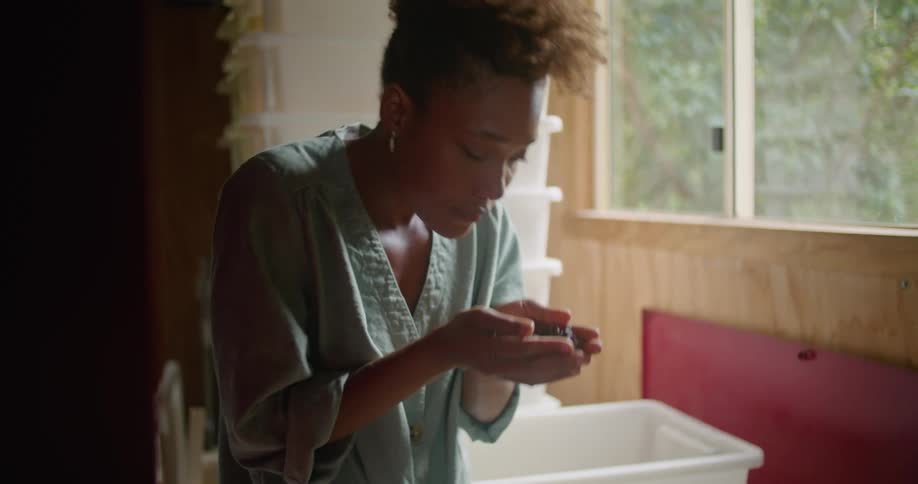 A woman brings a handful of coffee beans to her nose and sniffs