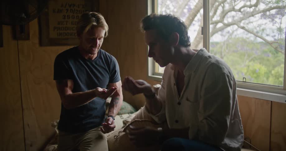 Man with white shirt and blonde man wearing dark blue t shirt smell coffee and talk about business in coffee warehouse