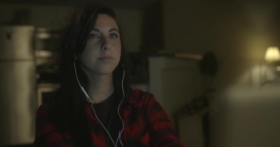 A woman is wearing earbuds as she opens her eyes