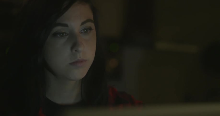 A dark haired woman sits at a computer