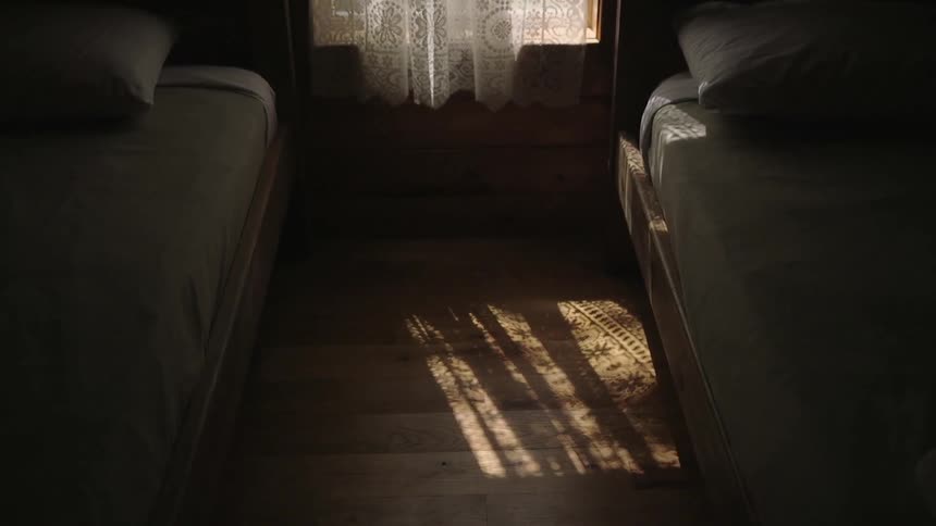 A dark room has a window with a curtain