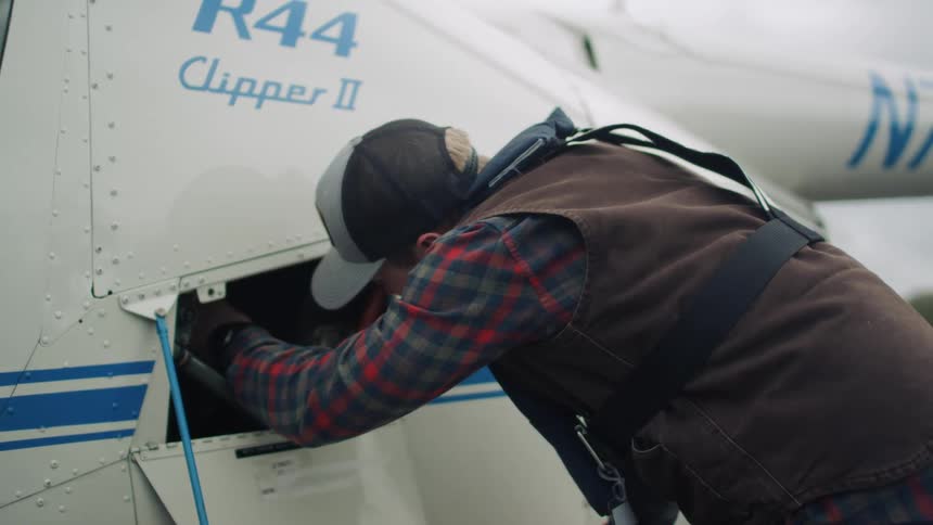 Man leans over working in helicopter compartment